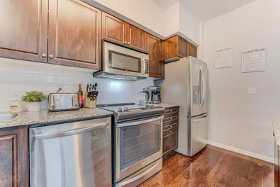 a kitchen with stainless steel appliances and wooden cabinets at Prime City Pad 2 Bedroom with CN Tower View in Toronto