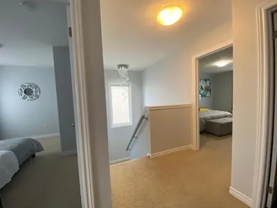 a bedroom with two beds and a hallway with a door at Stylish 3 Bdrm house- king bed, Netflix, parking in Kitchener
