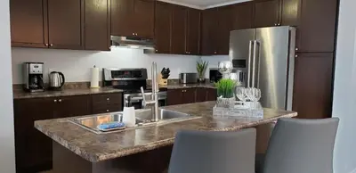 a kitchen with a sink and a refrigerator at Stylish 3 Bdrm house- king bed, Netflix, parking in Kitchener