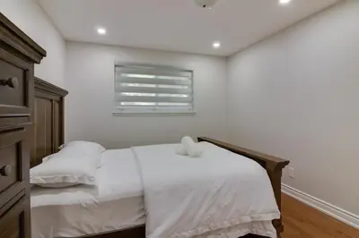 a white bedroom with two beds and a window at Beautiful House In Scarborough in Toronto