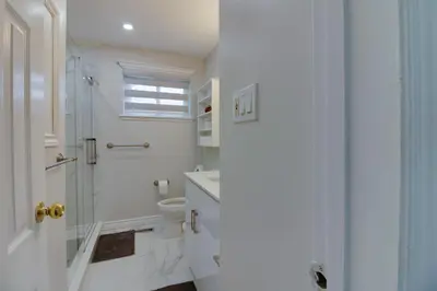 a white bathroom with a shower and a toilet at Beautiful House In Scarborough in Toronto