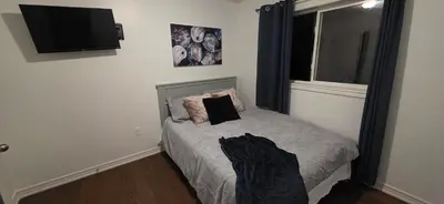 a bedroom with a bed with a television on the wall at short time rental in Kawartha Lakes