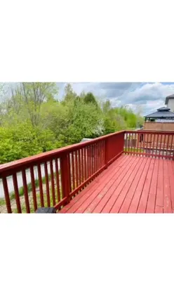 a balcony with a red wooden deck with trees at short time rental in Kawartha Lakes