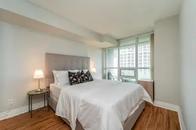 a bedroom with a large white bed with a window at Spacious 2 Bedroom plus Den, 2 Bath, Sleeps 5 with Balcony and Lakeview Downtown Toronto Condo in Toronto