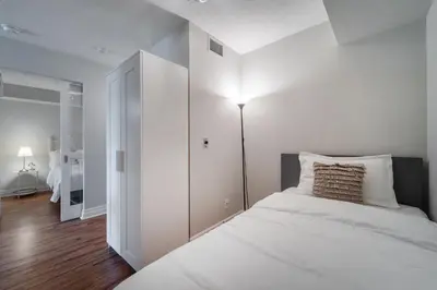 a white bedroom with a bed and a lamp at Spacious 2 Bedroom plus Den, 2 Bath, Sleeps 5 with Balcony and Lakeview Downtown Toronto Condo in Toronto