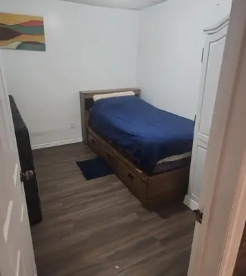 a small bedroom with a bed with blue sheets on it at Newly Furnished Modern Apartment in Welland