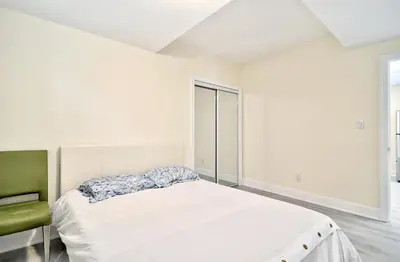 a white bedroom with a bed and a green chair at 50% discount Amazing 3 Bedrooms Guest Suite in Richmond Hill