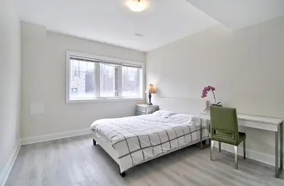 a white bedroom with a bed and a green chair at 50% discount Amazing 3 Bedrooms Guest Suite in Richmond Hill