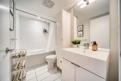 a white bathroom with a sink and a toilet at Stylish Downtown Toronto Suite with Free Parking in Toronto