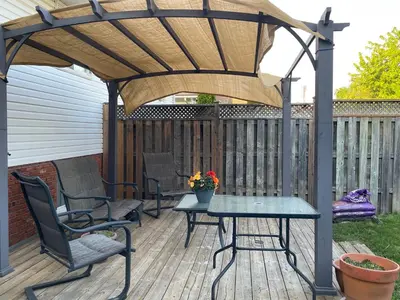 a pergola on a deck with chairs and a table at Private Suite in Niagara Falls in Niagara Falls