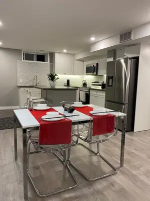 a kitchen with a table with chairs and a refrigerator at Brand new apartment with private entrance and patio in Guelph