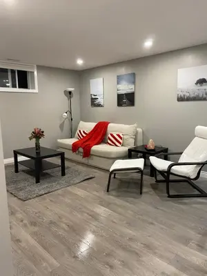 a living room with a white couch and two chairs at Brand new apartment with private entrance and patio in Guelph