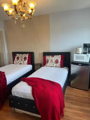 a bedroom with two beds with red pillows and a chandelier at Queen’s Gate Ecstasy Home in Brampton