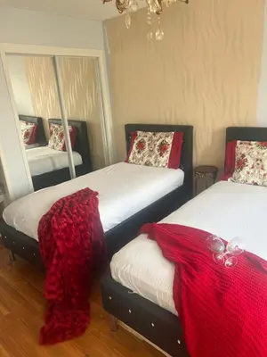 a bedroom with two beds with red blankets and mirrors at Queen’s Gate Ecstasy Home in Brampton