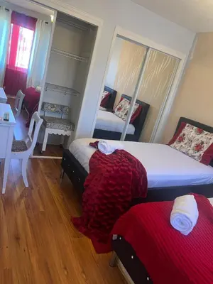 a bedroom with two beds and a table and a mirror at Queen’s Gate Ecstasy Home in Brampton