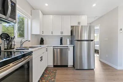 a kitchen with white cabinets and a stainless steel refrigerator at The Garden Retreat in Welland, On - 1BR,Free Parking and Workspace in Welland