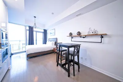 a bedroom with a bed and a table and a bed at RivetStays - The York in Toronto
