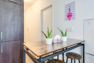 a kitchen with a wooden table and two stools at RivetStays - The York in Toronto