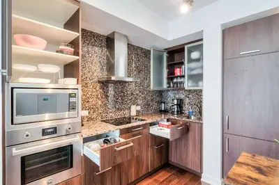 a kitchen with wooden cabinets and stainless steel appliances at RivetStays - The York in Toronto