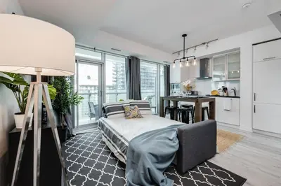 a bedroom with a large bed and a kitchen at RivetStays - The York in Toronto