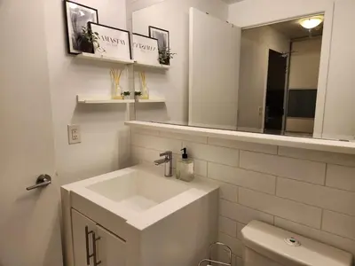 a white bathroom with a sink and a mirror at Queen St West Haven - Modern Loft, Downtown Toronto, Free Parking in Toronto