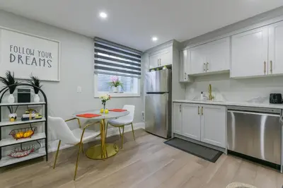 a kitchen with white cabinets and a table and chairs at 2 Bedroom Private Suite-Parking-Near Hospital and Airport in Oakville