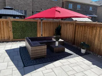 a patio with a red umbrella on a fence at 2 Bedroom Private Suite-Parking-Near Hospital and Airport in Oakville