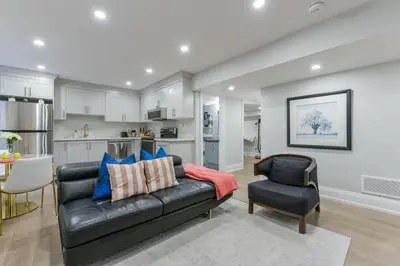 a living room with a black leather couch and a chair at 2 Bedroom Private Suite-Parking-Near Hospital and Airport in Oakville