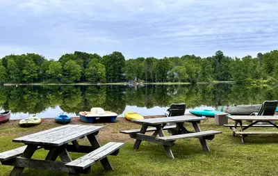 a group of picnic tables and boats on a lake at Lakefront Hideaway Resort 10 Total cabins-Lake View, Private Beach in Kawartha Lakes