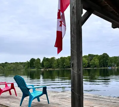 three chairs on a dock near a body of water at Lakefront Hideaway Resort 10 Total cabins-Lake View, Private Beach in Kawartha Lakes