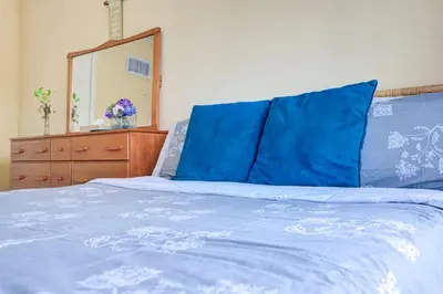 a bed with blue sheets and a dresser and a mirror at Brampton Retreat - Quiet 2BR Residential Area in Brampton