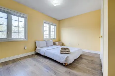 a bedroom with a large bed and two windows at Brampton Retreat - Quiet 2BR Residential Area in Brampton