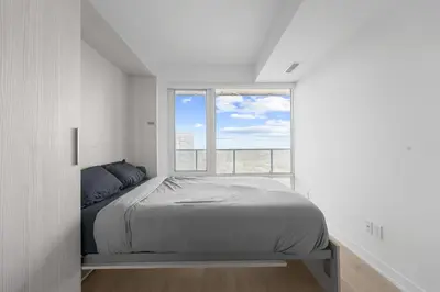 a bedroom with a bed and a large window at RentX Downtown 2-Bed Suite Gym WiFi in Toronto