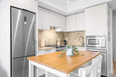 a kitchen with a wooden table and a refrigerator at RentX Downtown 2-Bed Suite Gym WiFi in Toronto