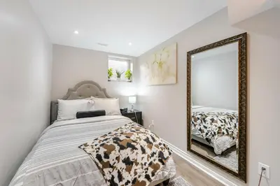 a bedroom with a bed and a mirror at Lovely Cozy Apartment in Brampton
