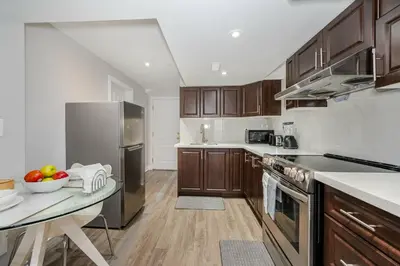a kitchen with wooden cabinets and stainless steel appliances at Lovely Cozy Apartment in Brampton