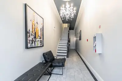 a hallway with a staircase and a chair and a chandelier at Newly Renovated Modern Studio on James St South in Hamilton