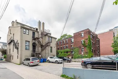 a building with cars parked in a parking lot at Newly Renovated Modern Studio on James St South in Hamilton