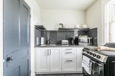 a white kitchen with a stove and a microwave at Newly Renovated Modern Studio on James St South in Hamilton