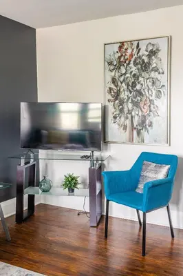 a living room with a blue chair and a tv at Newly Renovated Modern Studio on James St South in Hamilton