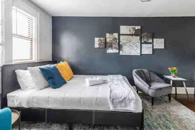a bedroom with a bed and a chair at Newly Renovated Modern Studio on James St South in Hamilton