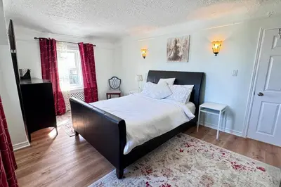 a bedroom with a large bed with a black frame at Near the Falls Two Bedroom - 5 min Walk to Clifton in Niagara Falls