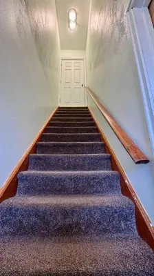 a flight of stairs with blue carpet and a white door at Near the Falls Two Bedroom - 5 min Walk to Clifton in Niagara Falls