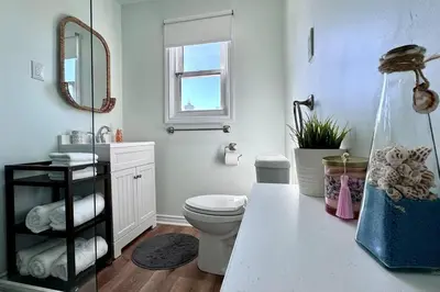 a bathroom with a toilet and a sink and a mirror at Near the Falls Two Bedroom - 5 min Walk to Clifton in Niagara Falls