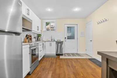 a kitchen with white cabinets and a wooden floor at Elegant & Private Apartment - Short Walk From Downtown in London