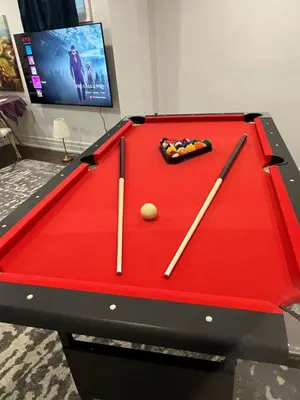 a red pool table with two cuesticks and a ball at cozy private guest suite in Richmond Hill
