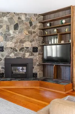 a living room with a television and a stone wall at Golden Field Farmhouse - stayinpec on IG in Bloomfield