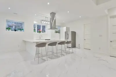a white kitchen with a sink and bar stools at Comfortable Room in Toronto next to Yorkdale mall in Toronto