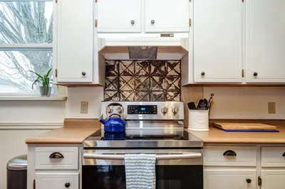 a kitchen with a stove with a blue tea kettle at The Marigold PEC Family Farmhouse country escape in West Lake