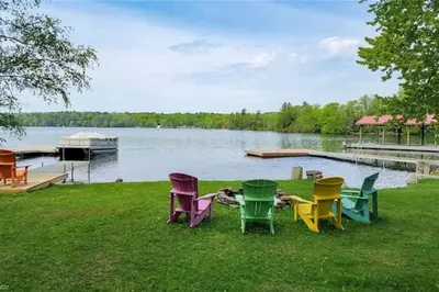 a group of chairs sitting on the grass near a lake at Waterfront Cottage - Fireplace - Kawartha in Lakefield